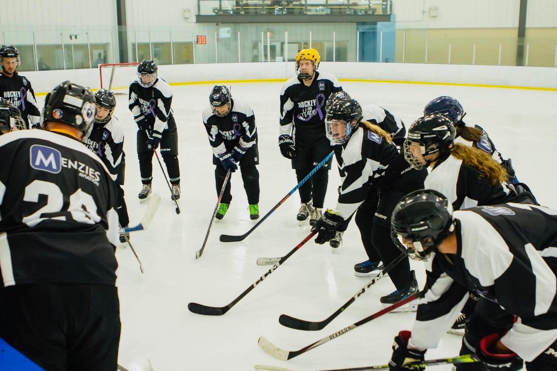 A team in black and white Hockey for Hope jerseys gathered in a circle at centre ice before a game