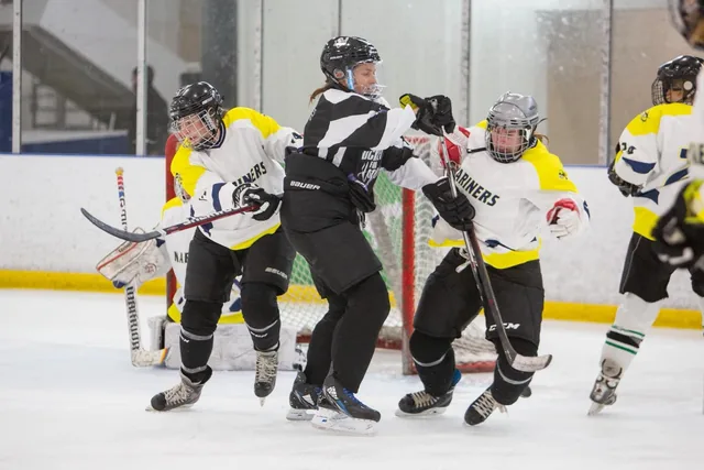 A Hockey for Hope player boxed out by two opponents in front of the goal